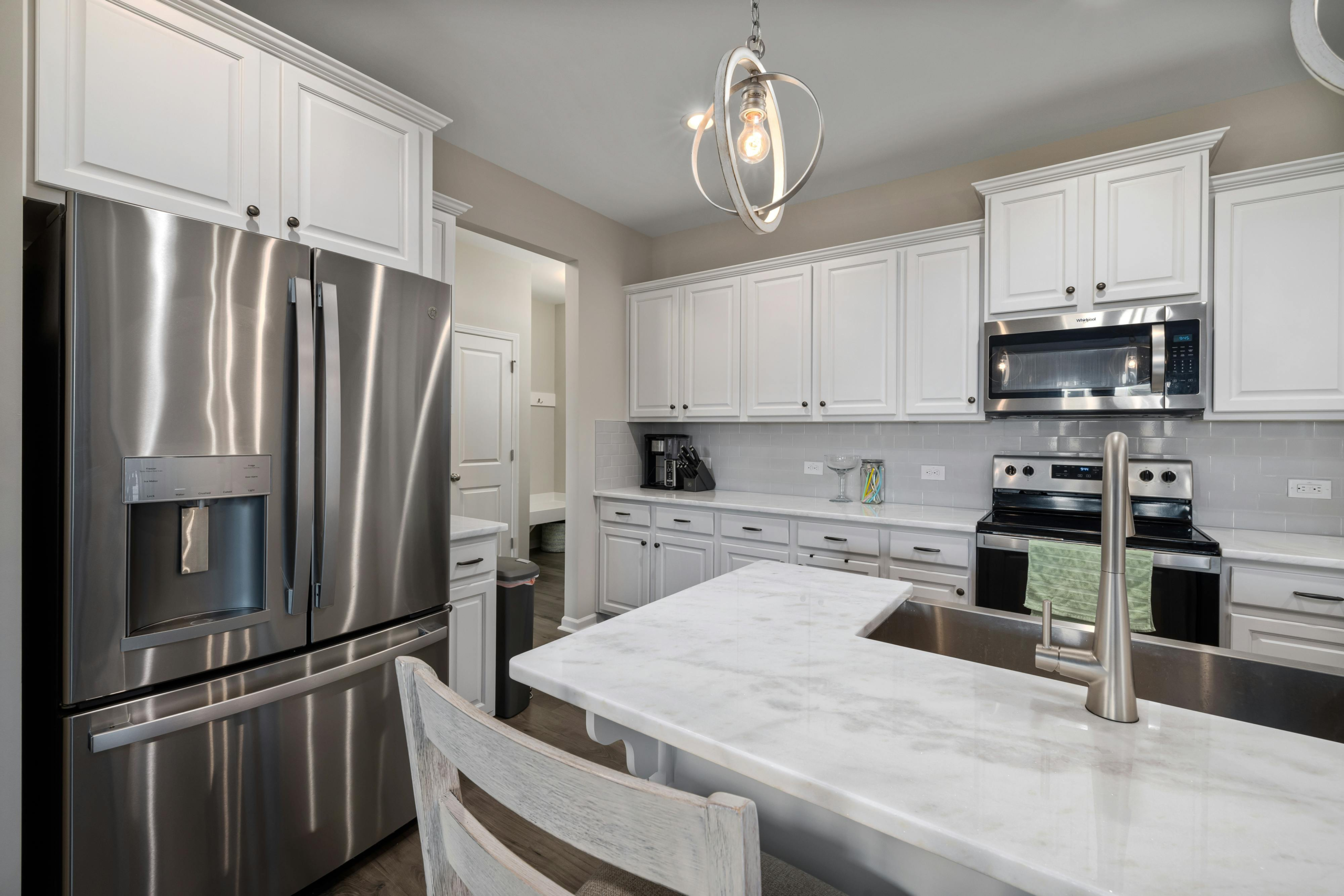 Elegant modern kitchen featuring white cabinetry and stainless steel appliances with marble countertops.